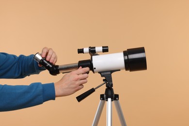 Astronomer setting up telescope on beige background, closeup