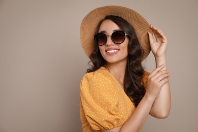 Photo of Beautiful young woman with straw hat and stylish sunglasses on beige background. Space for text