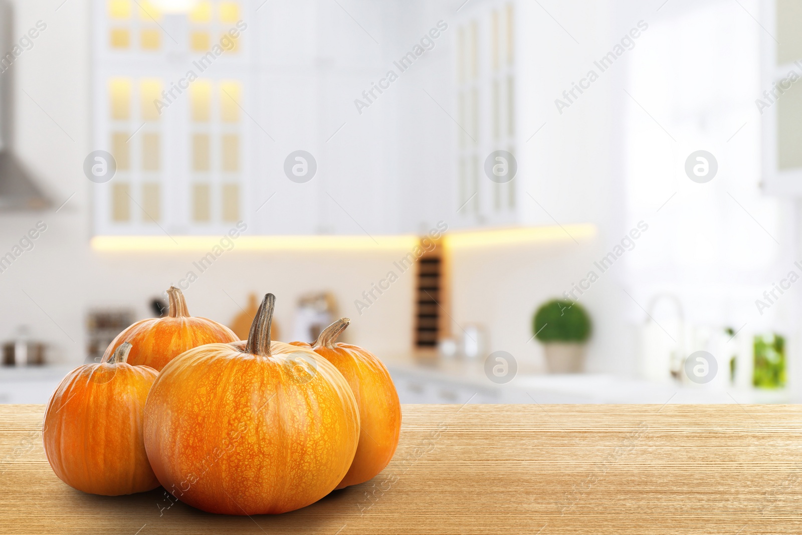 Image of Fresh pumpkins on wooden table in kitchen. Space for text