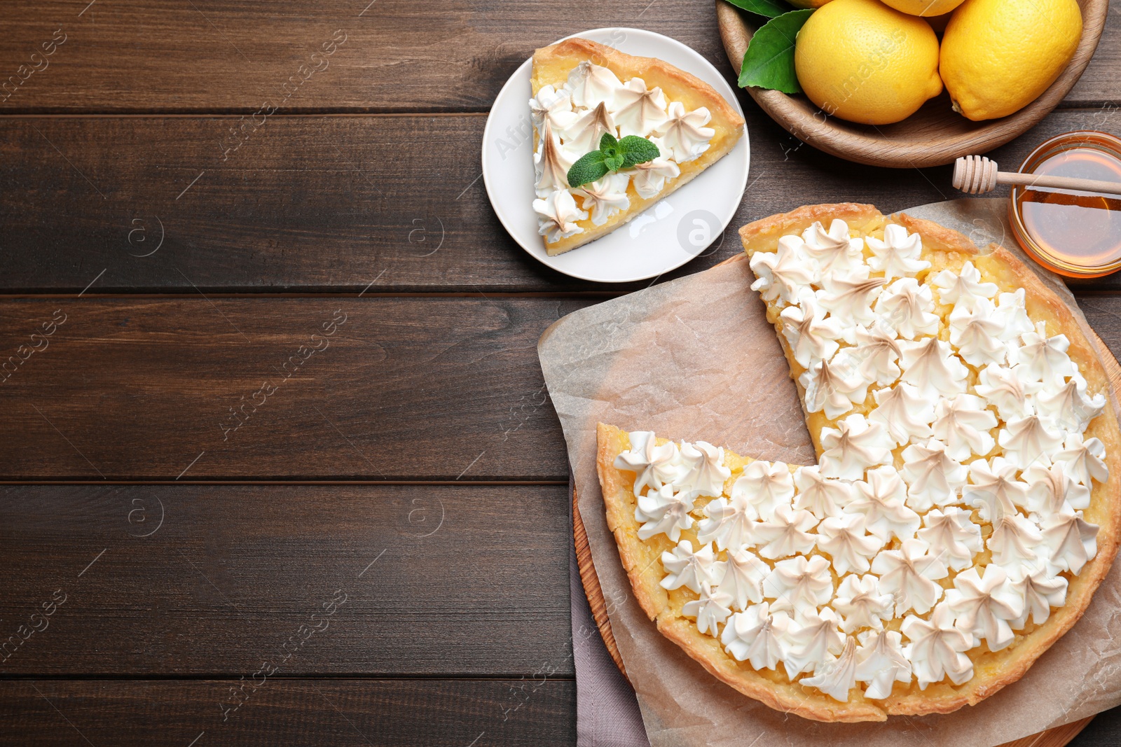 Photo of Cut delicious lemon meringue pie served on wooden table, flat lay. Space for text