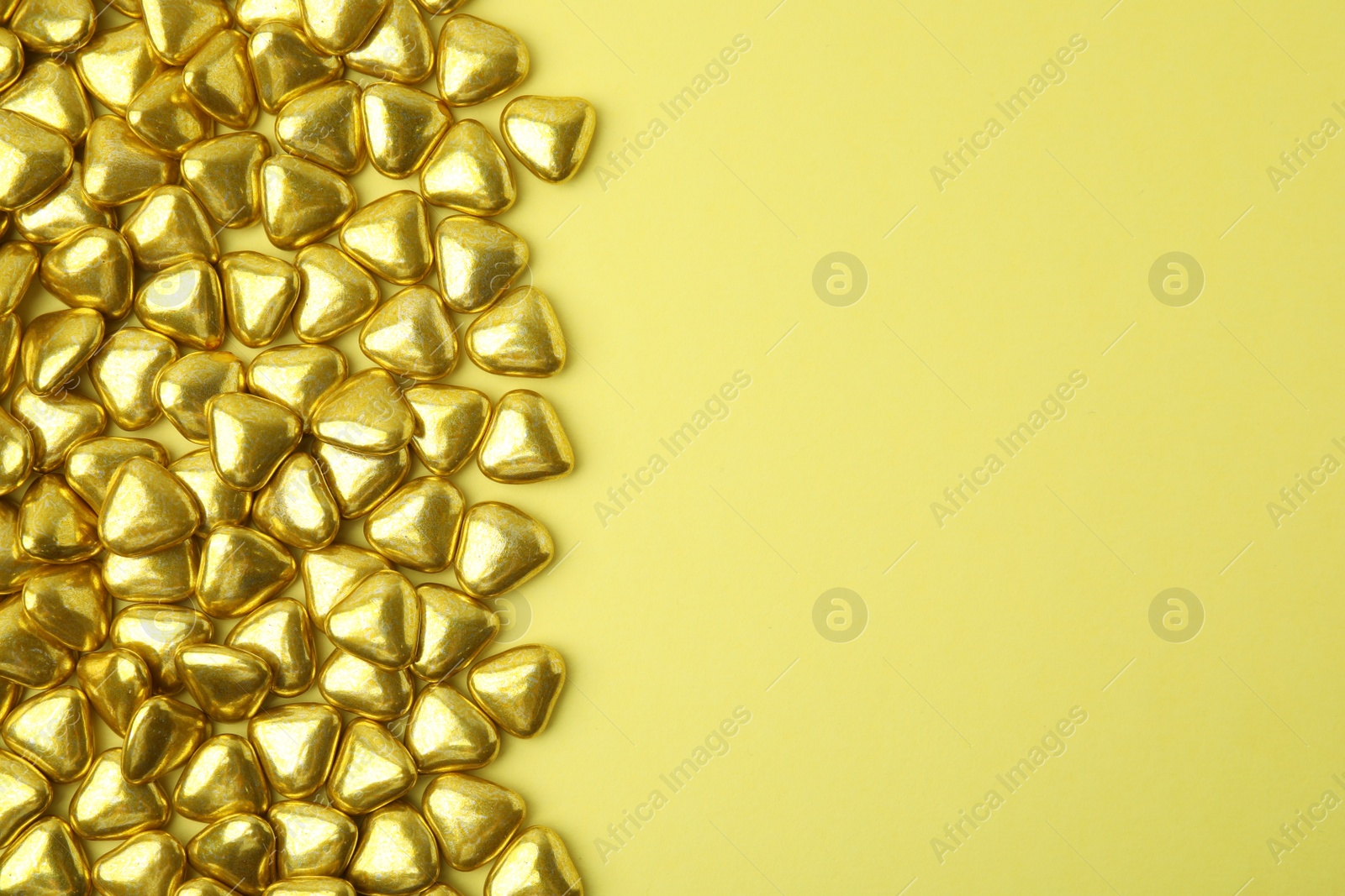 Photo of Many delicious heart shaped candies on yellow background, flat lay. Space for text