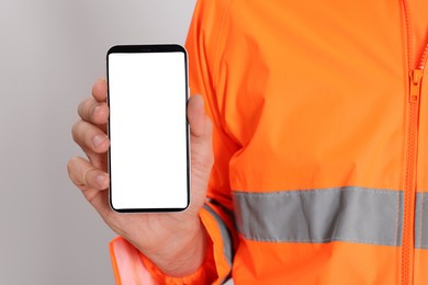 Man in reflective uniform with phone on white background, closeup
