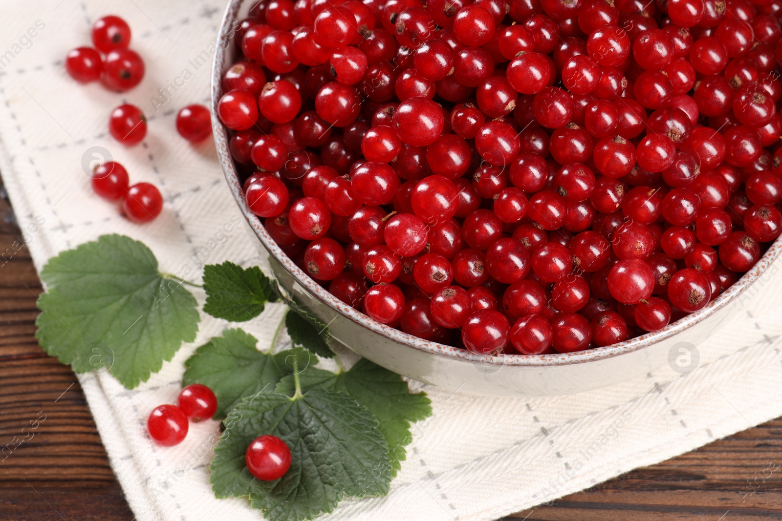 Photo of Ripe red currants and leaves on wooden table, closeup