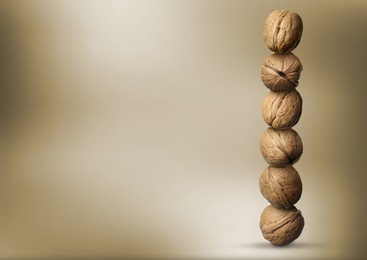 Image of Stacked walnuts on light brown gradient background, space for text