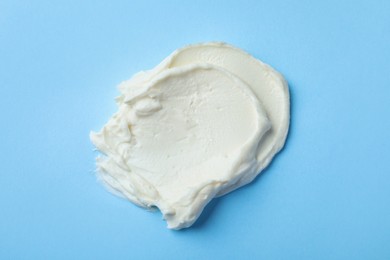 Photo of Smear of delicious cream cheese on light blue background, top view