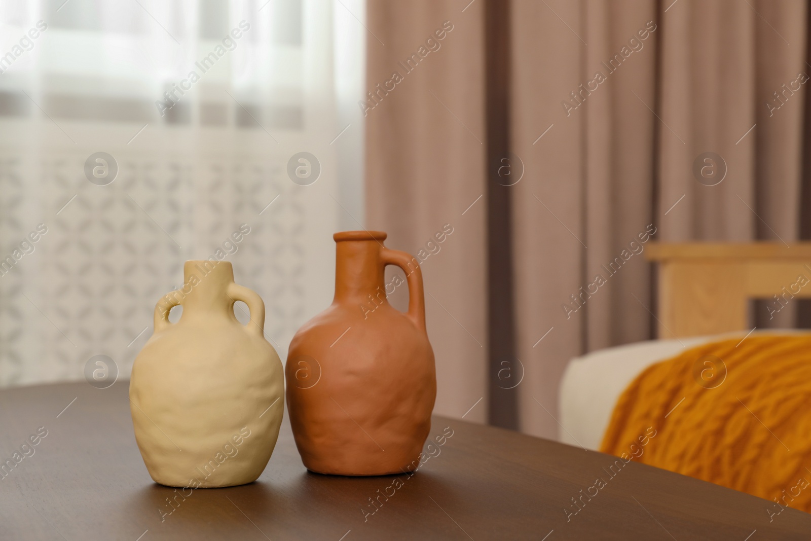 Photo of Different vases on wooden table and pastel window curtain in room, space for text