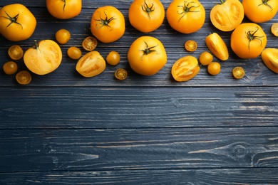 Photo of Ripe yellow tomatoes on blue wooden table, flat lay. Space for text