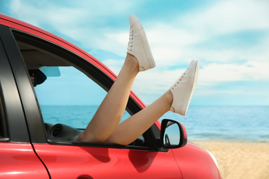 Photo of Woman showing legs from car, closeup. Summer vacation trip