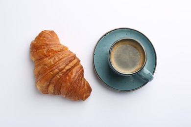 Delicious fresh croissant and cup of coffee on white background, flat lay