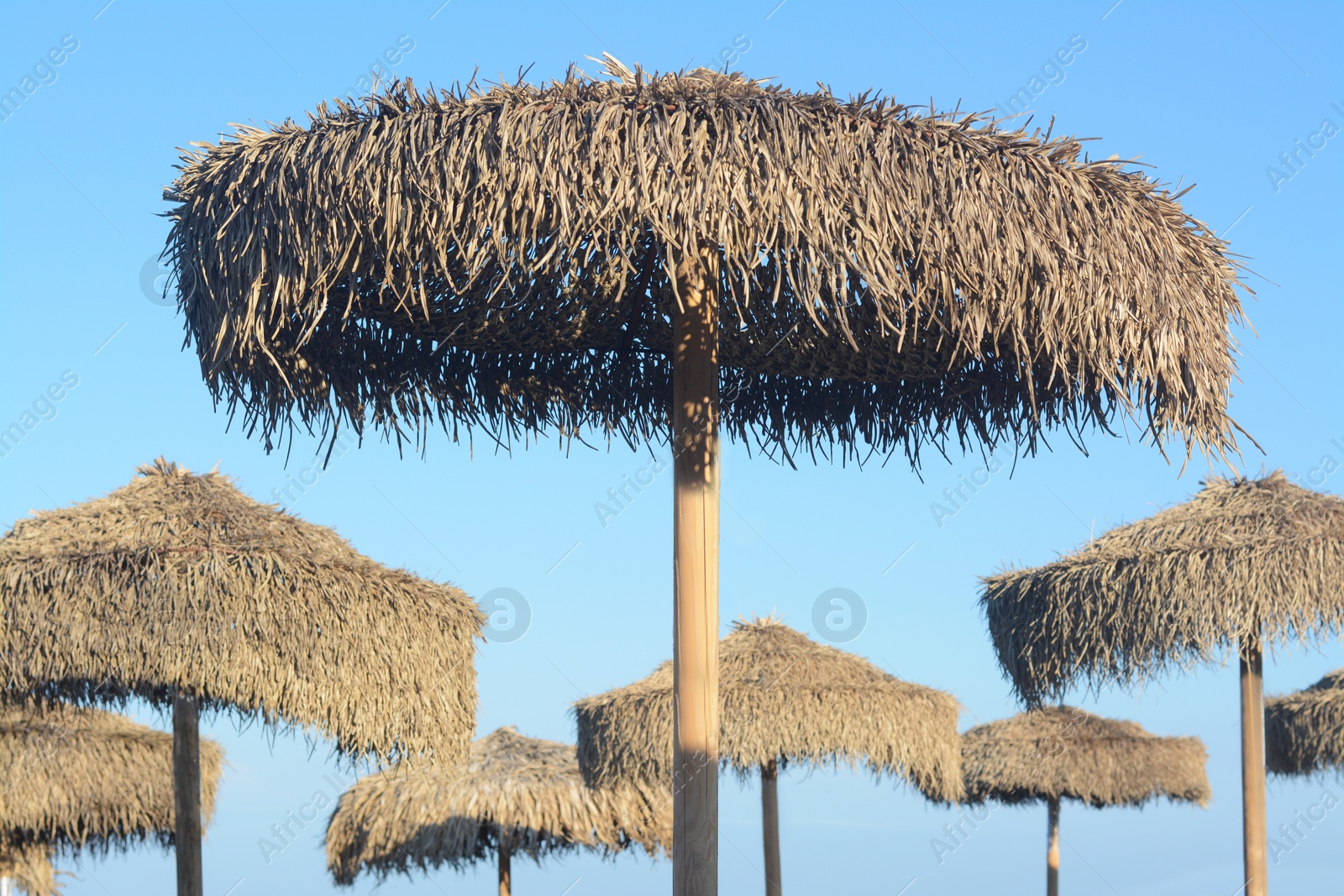 Photo of Beautiful straw beach umbrellas against blue sky