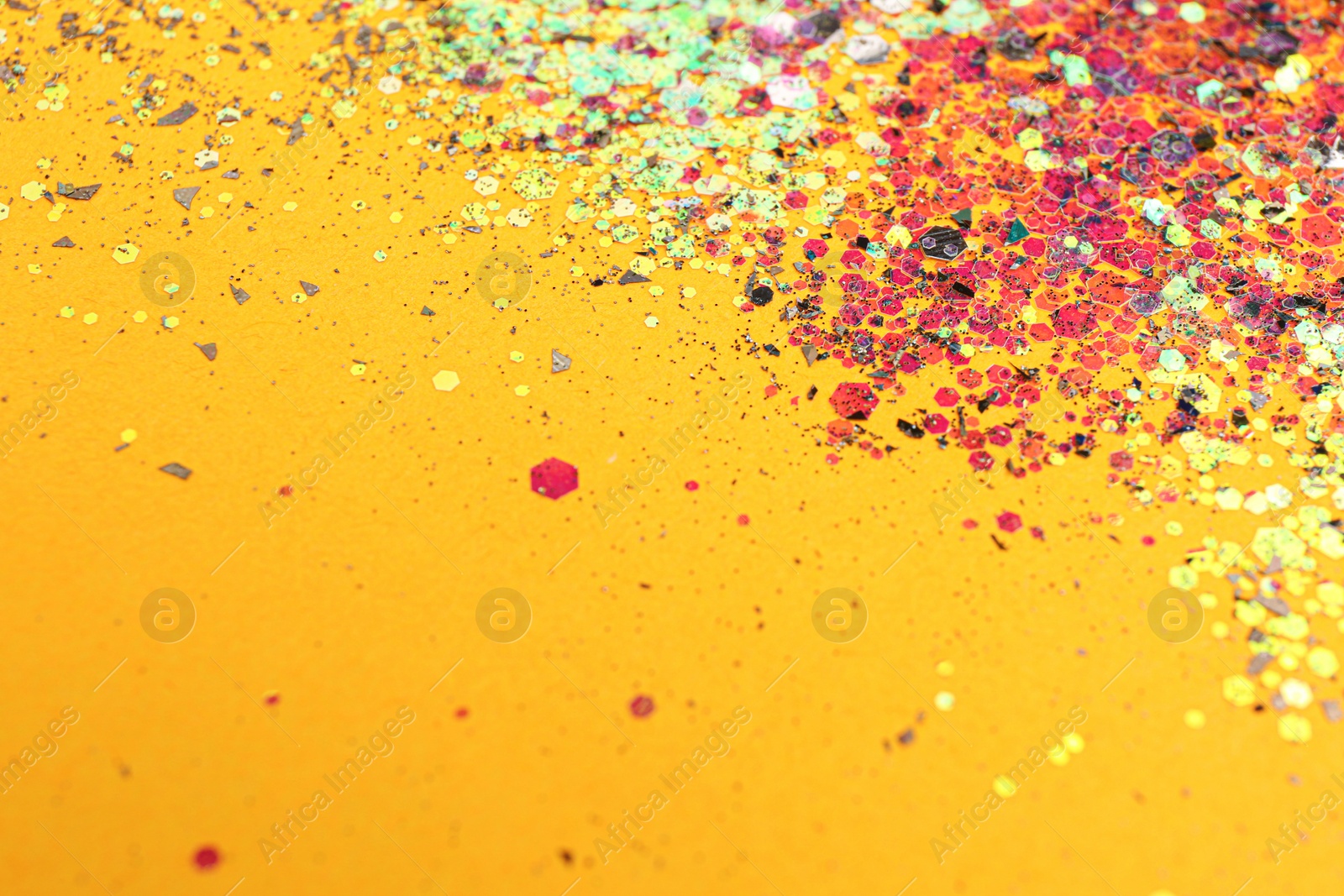 Photo of Shiny bright glitter on yellow background. Space for text