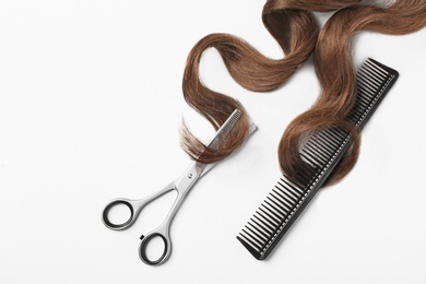 Photo of Brown hair, comb and thinning scissors on white background, top view. Hairdresser service
