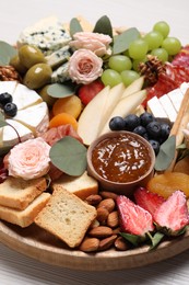 Wooden plate full of assorted appetizers on table, closeup