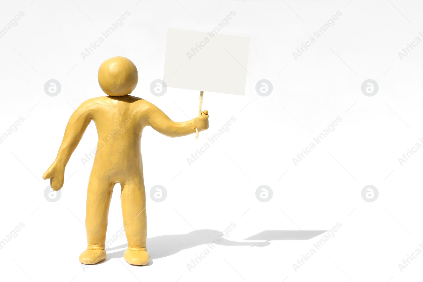 Photo of Human figure made of yellow plasticine holding blank sign on white background. Space for text