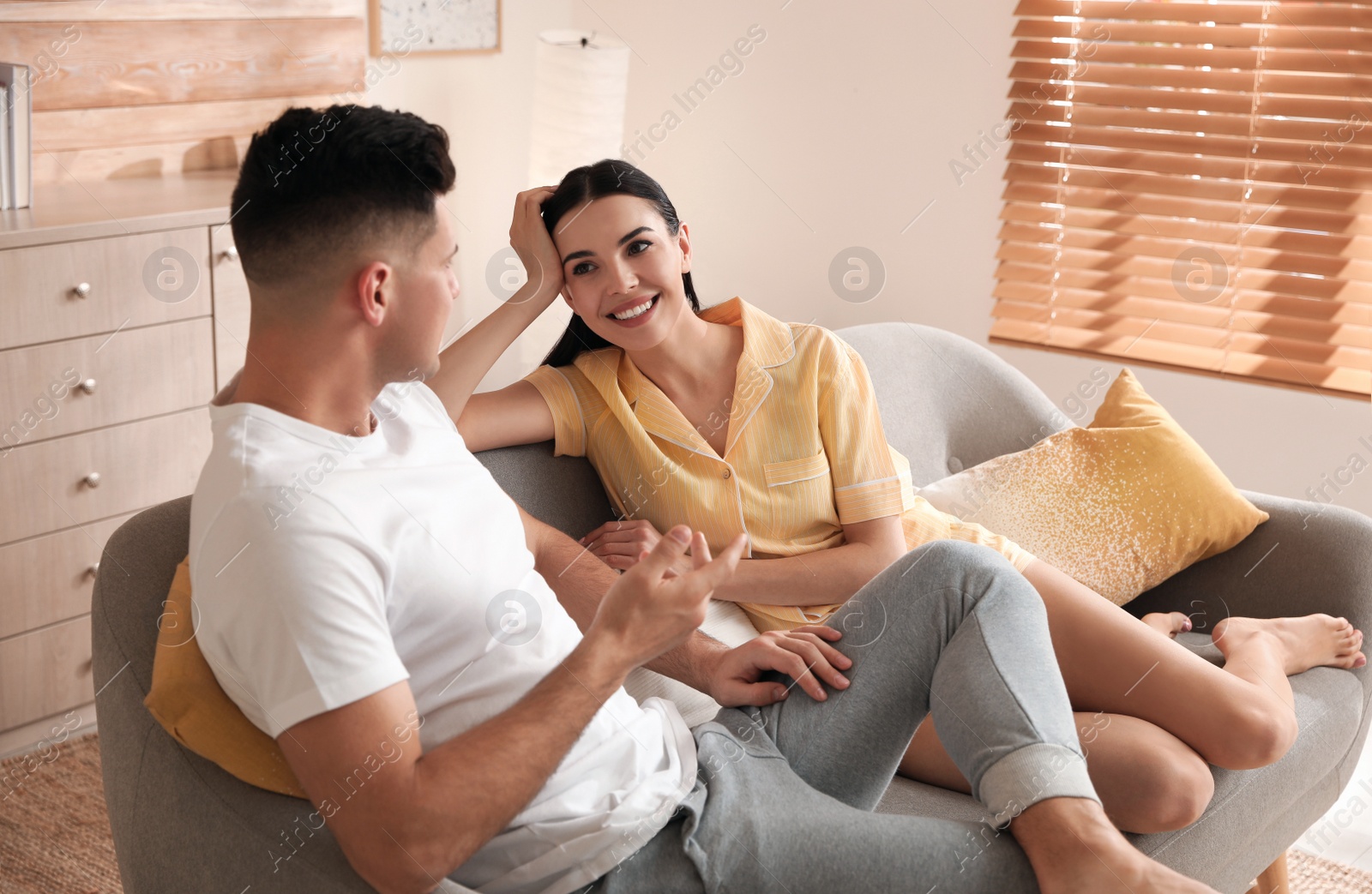 Photo of Happy couple in pyjamas spending time together on sofa at home