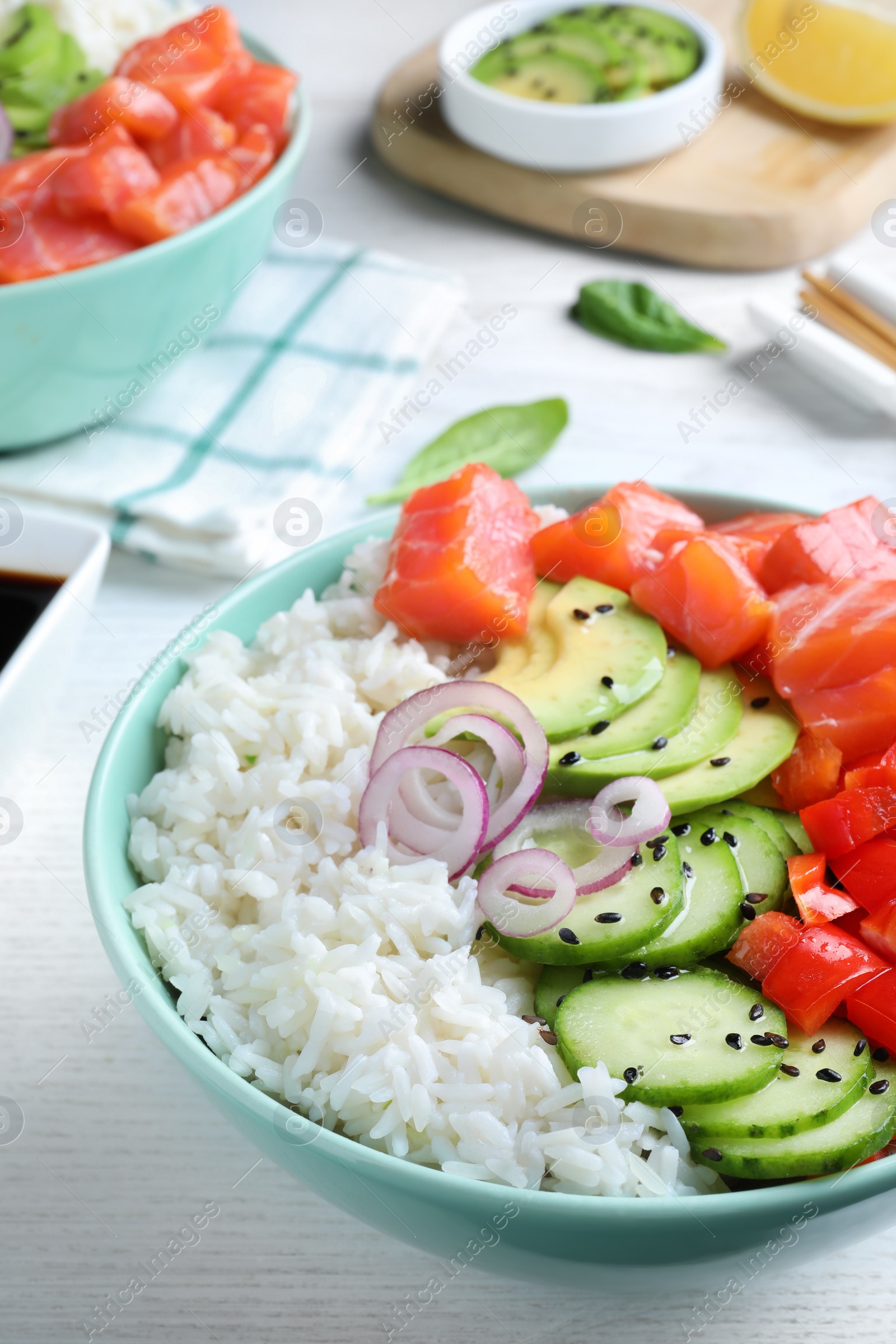Photo of Delicious poke bowl with salmon and vegetables served on white wooden table