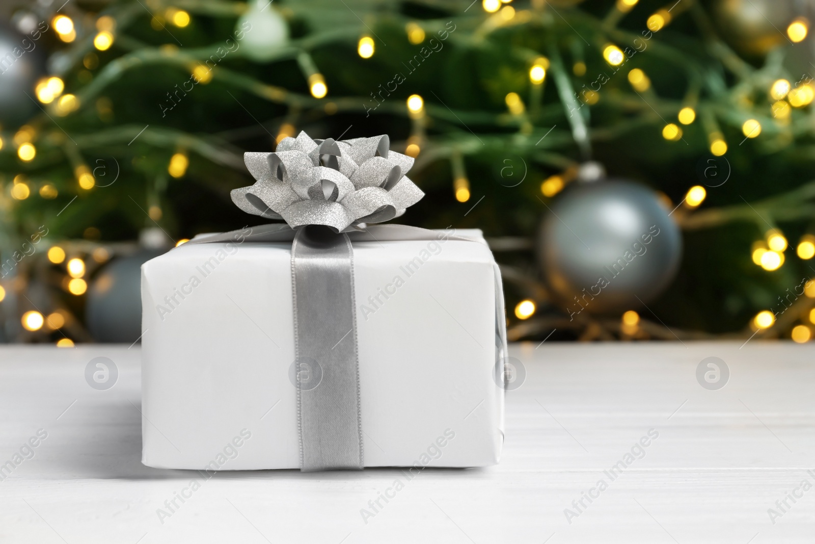 Photo of Beautiful gift box and blurred Christmas tree on background