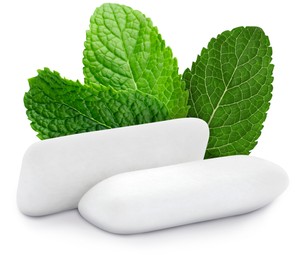 Menthol chewing gum pillows and mint leaves on white background