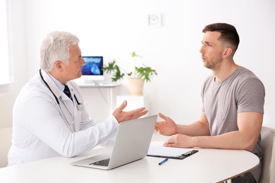 Photo of Male doctor working with patient in clinic. Cardiology consultation