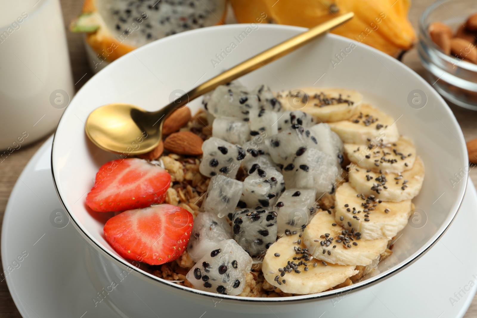 Photo of Pitahaya, banana, almond and strawberry in bowl on table, closeup