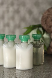 Photo of Mini bottles of cosmetic products on grey textured table