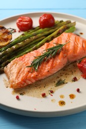 Photo of Tasty grilled salmon with tomatoes, asparagus and spices on table, closeup