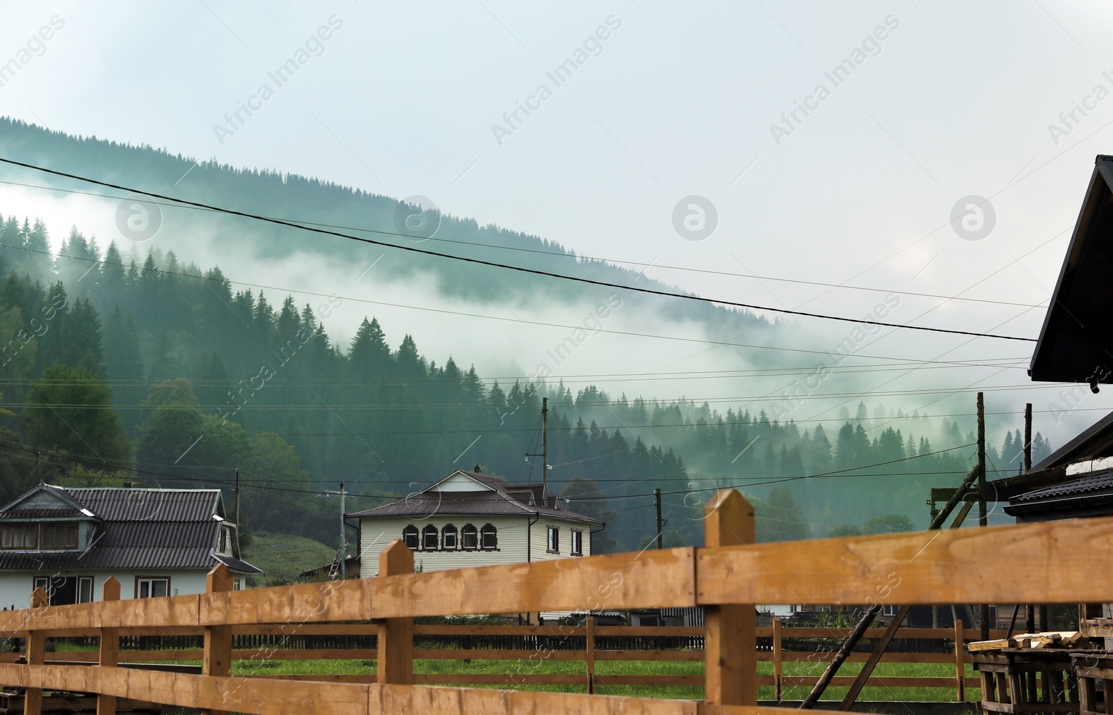 Photo of Picturesque view of village near mountains in foggy morning