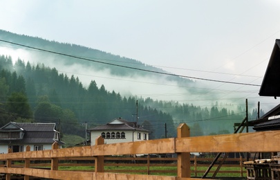 Picturesque view of village near mountains in foggy morning