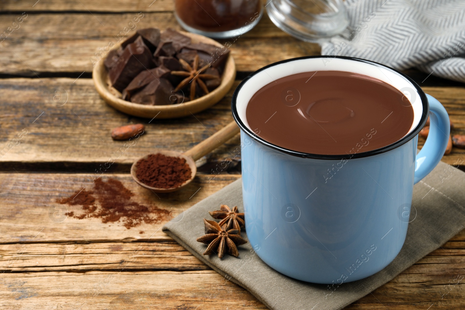 Photo of Yummy hot chocolate in mug on wooden table, space for text