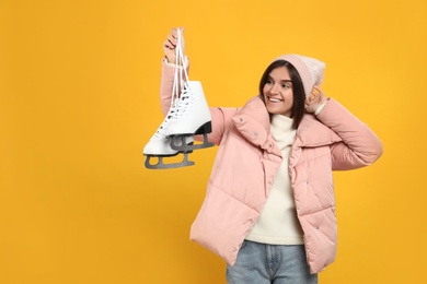 Photo of Emotional woman with ice skates on yellow background