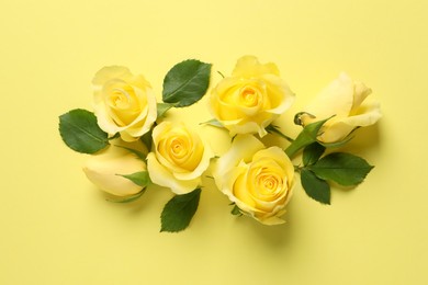 Photo of Beautiful roses on yellow background, flat lay