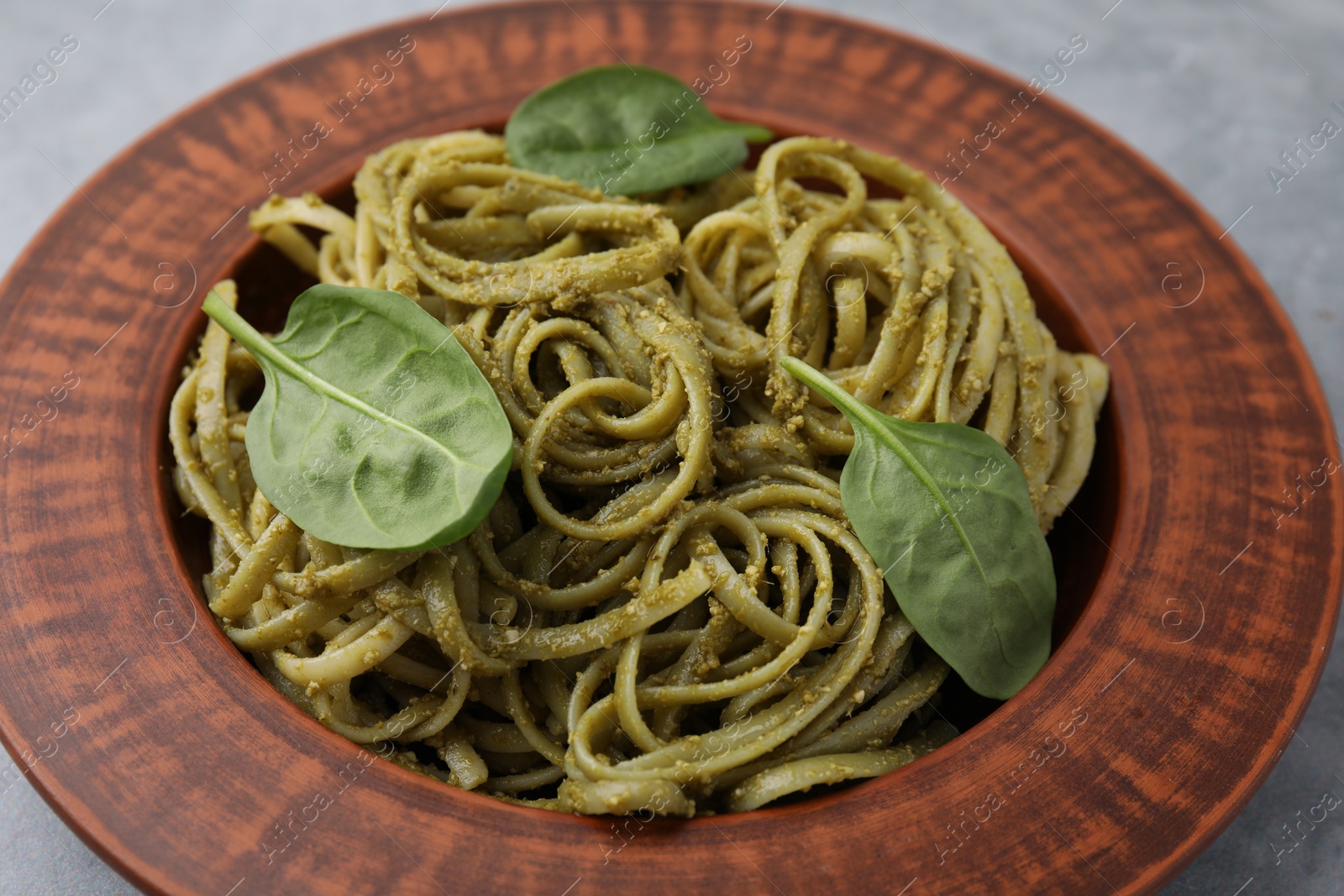 Photo of Tasty pasta with spinach on grey table, closeup