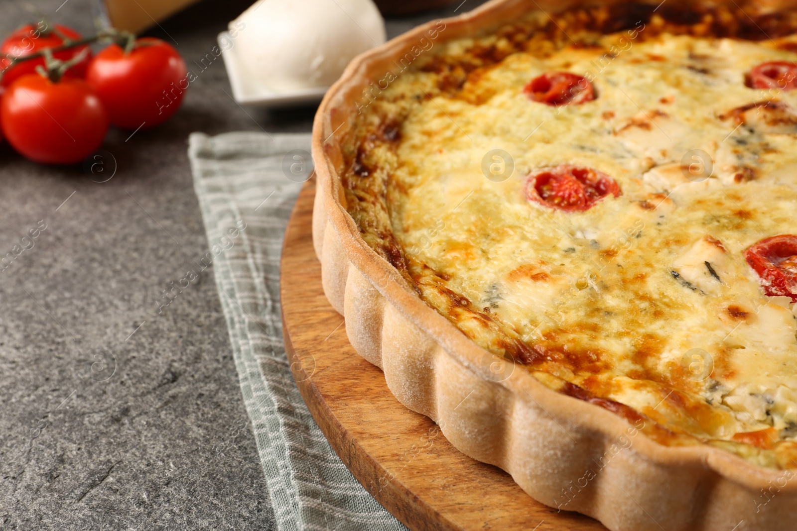 Photo of Delicious homemade cheese quiche and ingredients on gray table, closeup