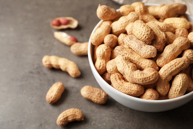 Photo of Bowl with peanuts in shell on table