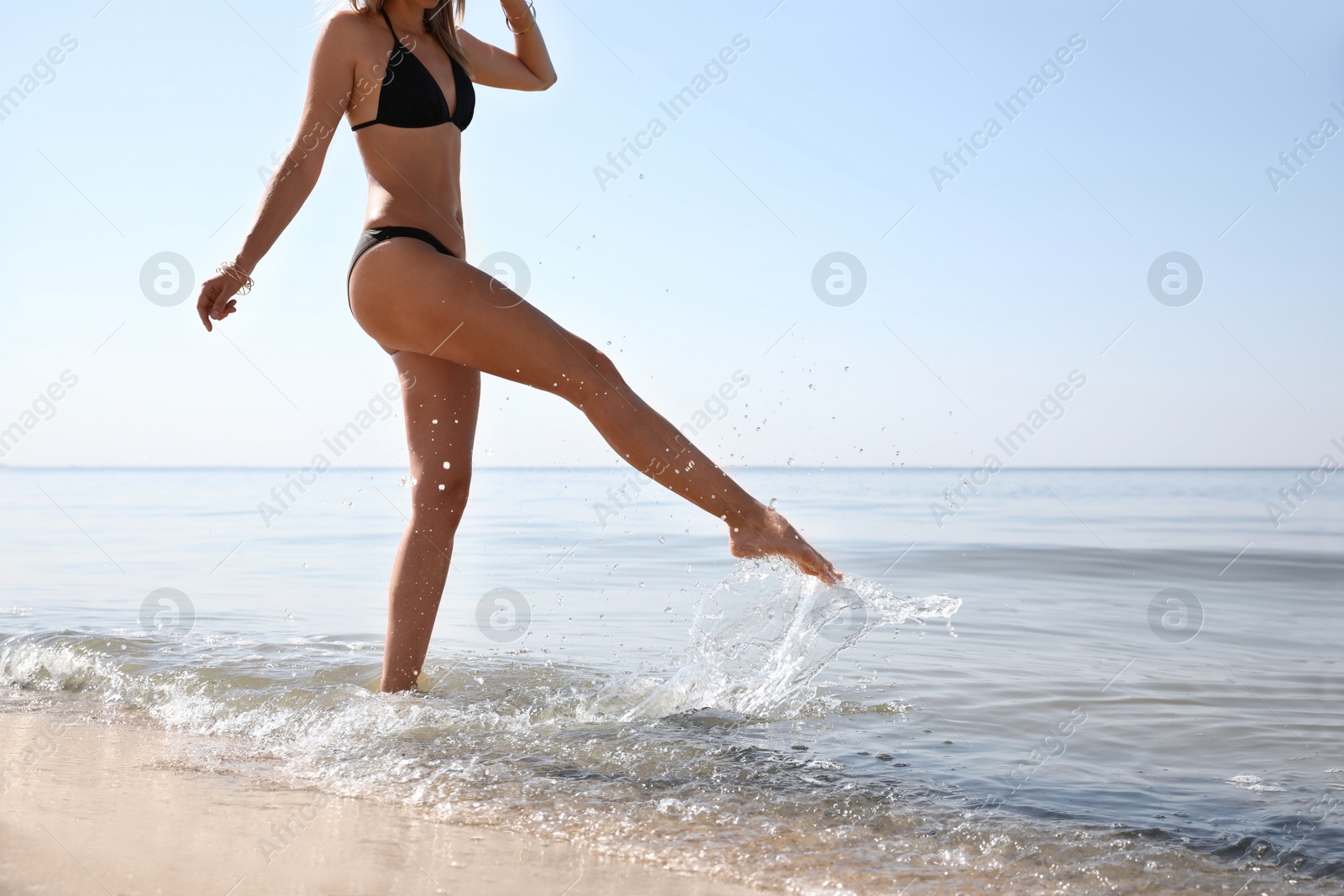 Photo of Young woman with beautiful body on beach, closeup