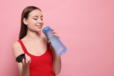 Beautiful young woman with transparent bottle on pink background, space for text