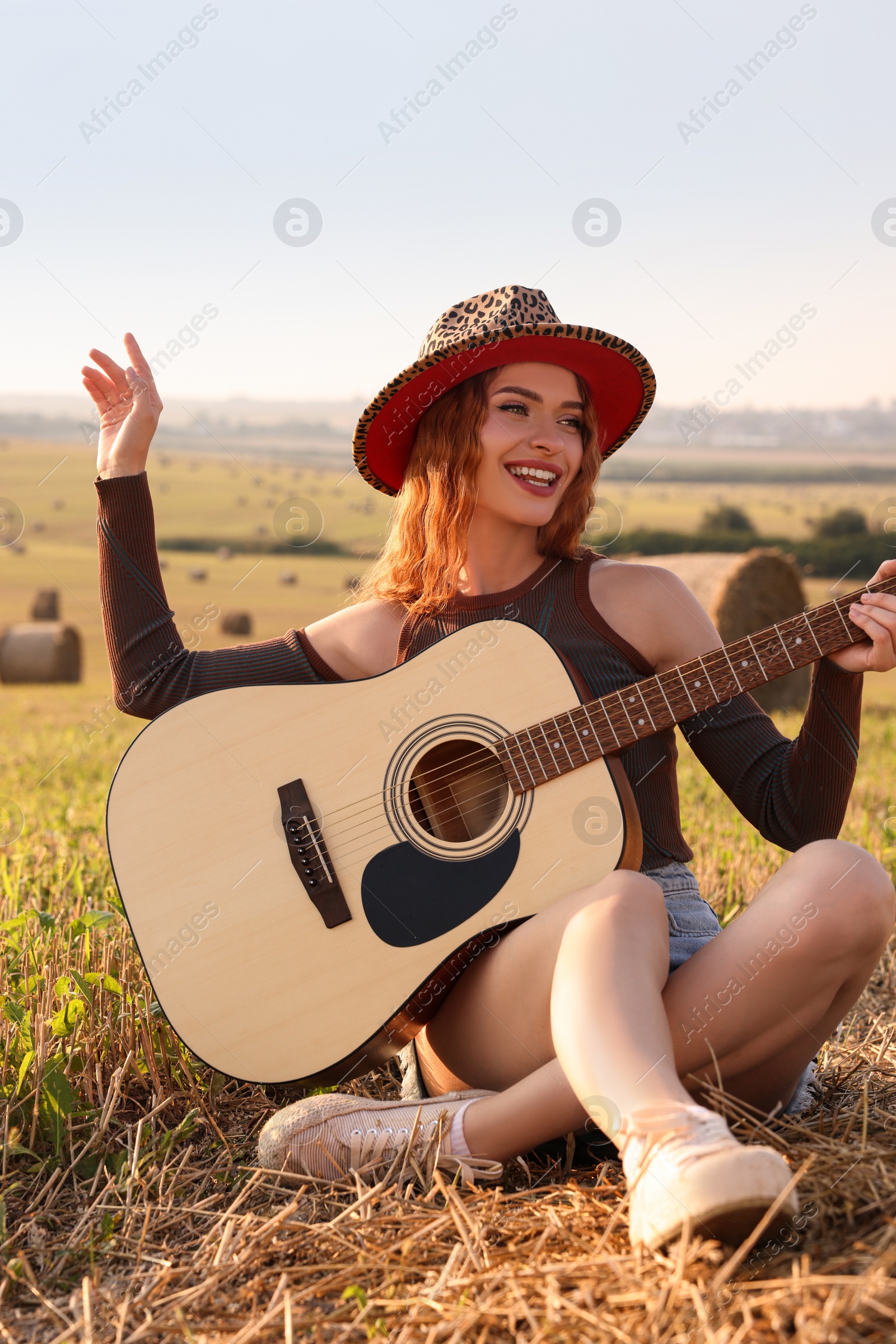 Photo of Beautiful happy hippie woman with guitar in field