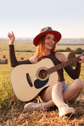 Beautiful happy hippie woman with guitar in field