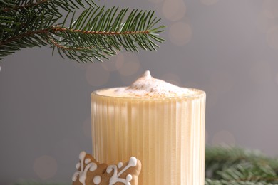 Tasty eggnog and fir branches on grey background, closeup