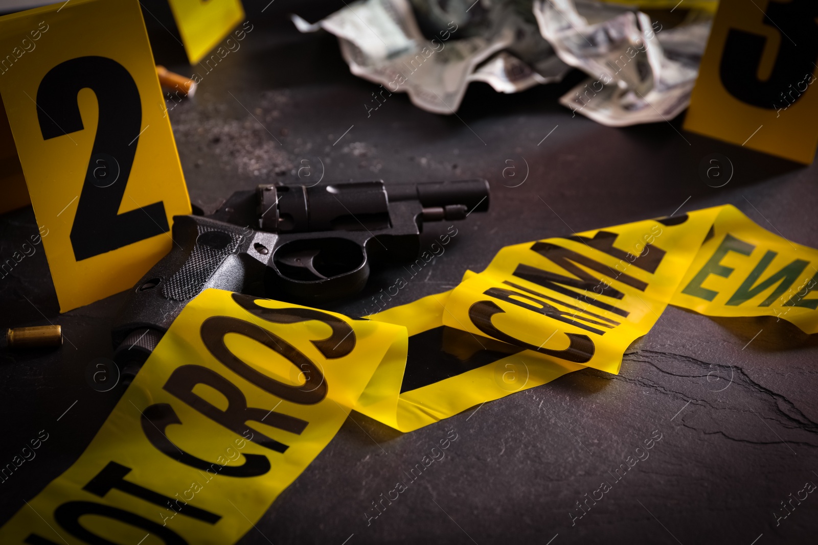 Photo of Composition with gun on black slate table. Crime scene