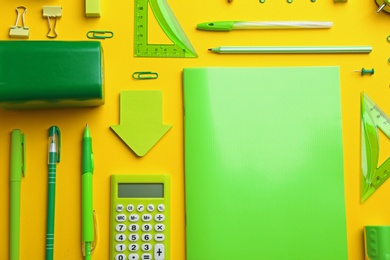 Photo of Green school stationery on yellow background, flat lay