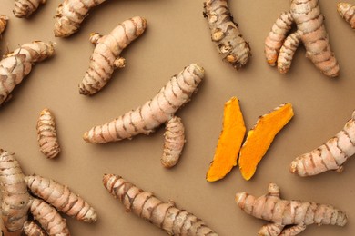 Photo of Many raw turmeric roots on light brown table, flat lay