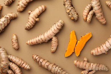 Many raw turmeric roots on light brown table, flat lay