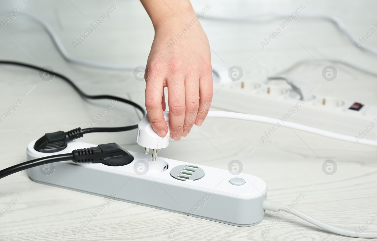 Photo of Woman inserting power plug into extension cord on floor, closeup with space for text. Electrician's professional equipment