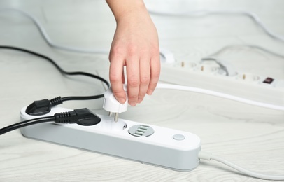 Photo of Woman inserting power plug into extension cord on floor, closeup with space for text. Electrician's professional equipment