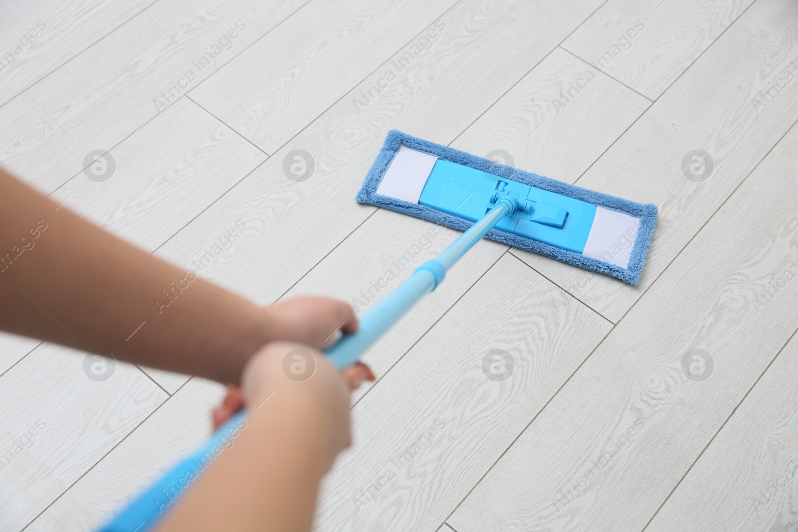 Photo of Woman cleaning parquet floor with mop, closeup