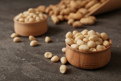 Photo of Shelled peanuts in wooden bowl on table. Space for text