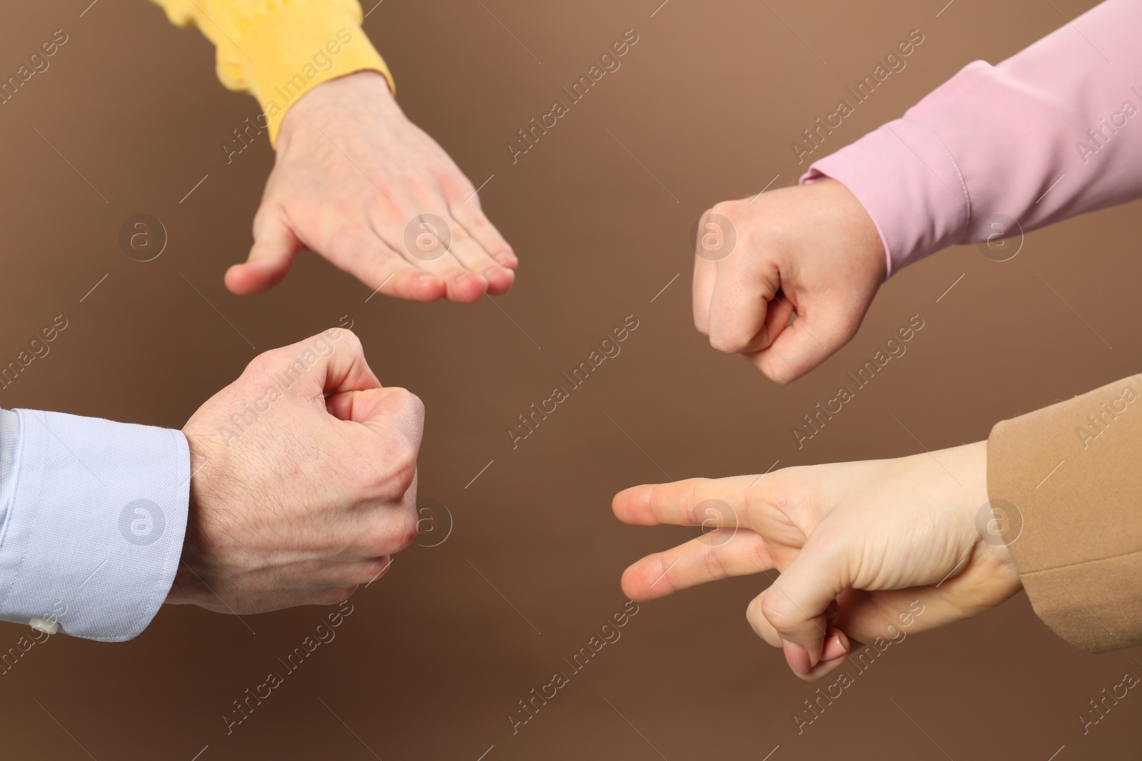 Photo of People playing rock, paper and scissors on brown background, closeup