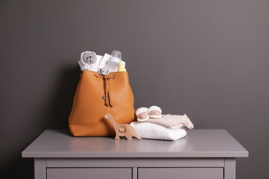 Photo of Mother's bag with baby's stuff on commode near gray wall