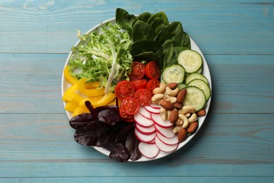 Balanced diet and vegetarian foods. Plate with different delicious products on light blue wooden table, top view